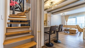 A modern interior with a wooden staircase, a dining area with a sofa and chairs, and a kitchen area with cabinets and a countertop. - 4 bedroom lovely apartment in Medulin (Medulin)