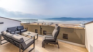 A rooftop terrace with a sofa, chair, and table, overlooking a calm body of water and distant hills. - 4 bedroom lovely apartment in Medulin (Medulin)
