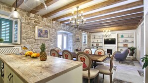 Un'area pranzo rustica con parete in pietra, travi in legno e un lampadario.