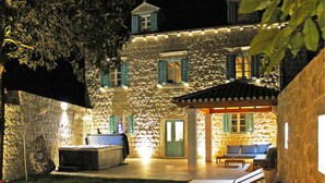 Un edificio in pietra con numerose finestre e una zona salotto all'aperto coperta.