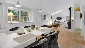 A spacious dining area with a long table, wicker chairs, and pendant lighting. - 4 bedroom stunning home in Nexø (Nexø)