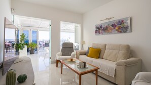 A modern living room with a sofa, armchairs, a coffee table, and a painting on the wall.