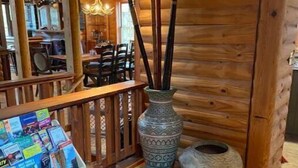 Un interior de madera con barandilla, suelo y un jarrón decorativo con ramas.