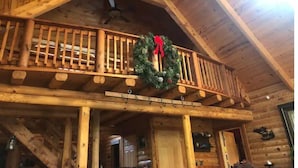 Una cabaña de madera con balcón, adornada con un adorno navideño.