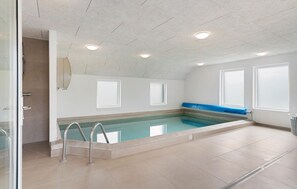 Ein Swimmingpool mit blauer Umrandung, einem Glastür-Eingang und einer Decke mit eingelassener Beleuchtung.