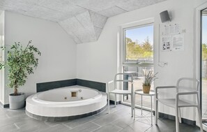 Relax in a spacious room with a large jacuzzi tub, a window offering views of the outdoors, and a potted plant.