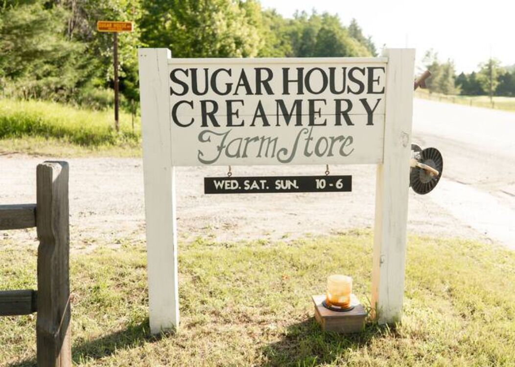 En skylt för Sugar House Creamery Farm Store med information om öppettider och vilka dagar butiken är öppen.