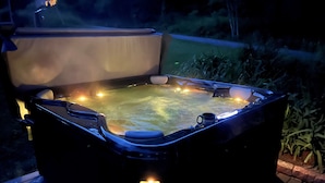 A hot tub with a wooden deck and a garden view. - Adirondack Fall Haven: Hot Tub, Fireplace, Coffee Bar, Dogs Welcome! (Upper Jay)