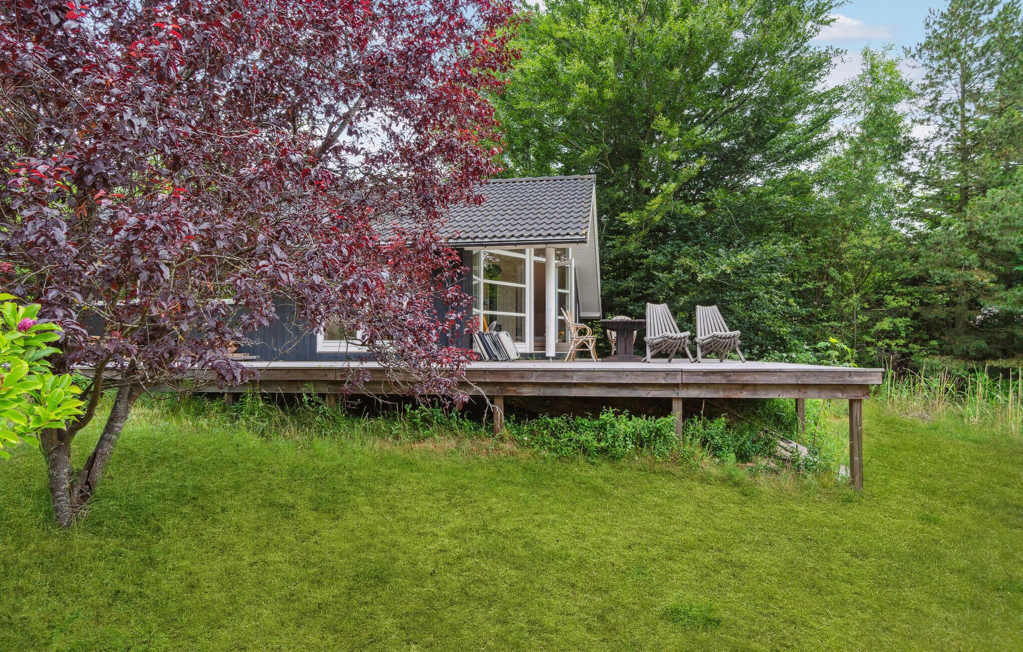 A wooden deck with a house, two chairs, and a table.