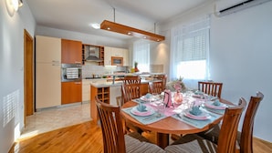 Una cocina moderna con armarios de madera, una isla central y una zona de comedor con una mesa redonda dispuesta para cuatro.
