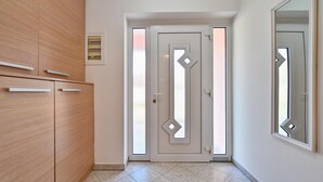 Un pasillo con un armario de madera, una puerta con un diseño geométrico y un espejo en la pared.