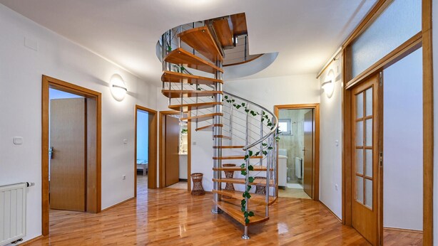 Un interior moderno con una escalera espiral, pisos de madera y vistas al baño.