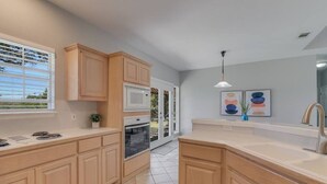 Una cocina moderna con armarios de madera, encimera blanca y horno integrado.