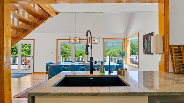 A modern kitchen with a large island, wooden beams, and a view of the outdoors. - Luxury Home with MountainViews•PoolTable•Chefs Kitchen•FirePit (Lake Lure)