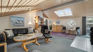 Un loft espaiós amb sostre alçat, obertures al sostre, una zona de seients acollidora amb sofà i cadires, taula de dinar i zona de cuina amb armari i una planta.