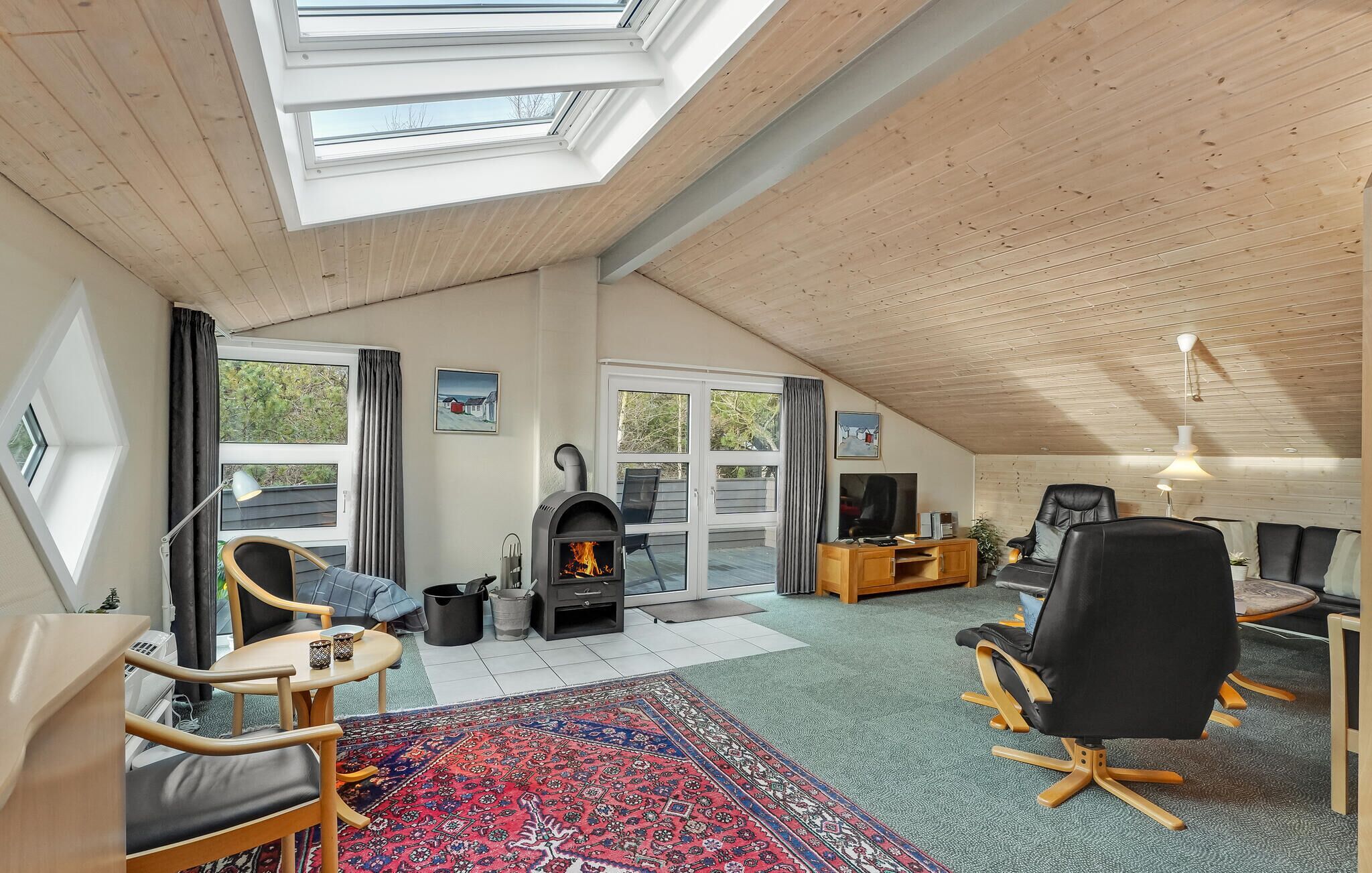 Una sala de estar acogedora con chimenea, techo de madera y ventanas amplias.