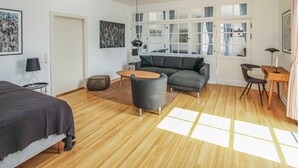 A modern living room with a sofa, a coffee table, and a small round table. There is a door leading to another room and a window with curtains. - Amazing apartment in Samsø with WiFi (Samsø)