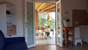 Una stanza con una porta scorrevole in vetro che si apre su un patio esterno con tavolo e sedie.
