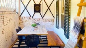 Un espace de restauration extérieur accueillant, avec une table et des chaises en bois, un luminaire suspendu et un panneau décoratif mural.