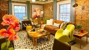 Un salon chaleureux avec un mur en briques, un plafond en bois et une grande fenêtre.