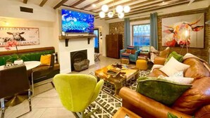 Un salon chaleureux avec une cheminée, un téléviseur et un coin salon confortable.