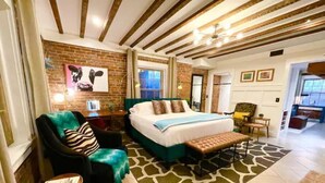 Une chambre d’hôtel avec un lit, une chaise, un banc, un bureau et une fenêtre.