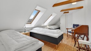 Een moderne slaapkamer met een hoogslaper, dakramen, een houten bureau en een stoel.