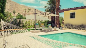 Area piscina con sedie a sdraio, un'amaca e un gazebo che offre ombra.