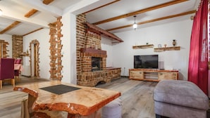 Una sala rústica con paredes de ladrillo visto, una mesa de madera, un sofá y un televisor.