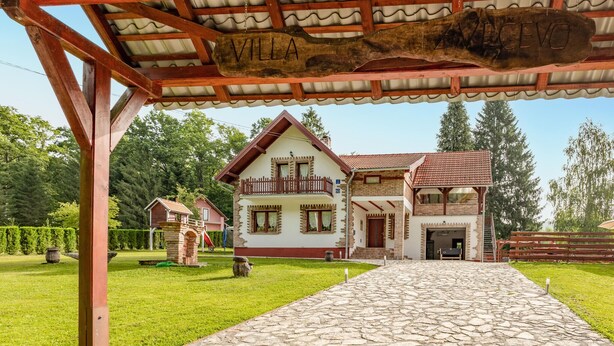 Una villa tradicional con un sendero de piedra que conduce a la entrada, rodeada de exuberante vegetación.