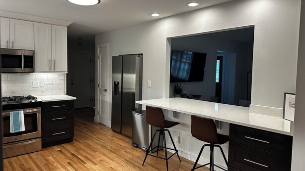 A modern kitchen with stainless steel appliances, wooden flooring, and a large window. - Quiet neighborhood near it ALL, Sleeps 12, Pet Friendly, Swamp Cooler (Centennial)