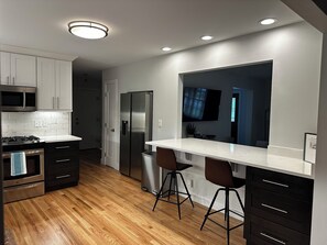 A modern kitchen with stainless steel appliances, wooden flooring, and a large window. - Quiet neighborhood near it ALL, Sleeps 12, Pet Friendly, Swamp Cooler (Centennial)