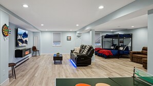 A spacious living area with a flat-screen TV, a fireplace, a comfortable sofa, a gaming table, and a bunk bed. - Quiet neighborhood near it ALL, Sleeps 12, Pet Friendly, Swamp Cooler (Centennial)