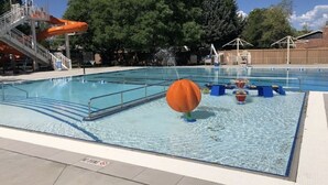 A swimming pool with a water slide, a lifeguard stand, and a covered seating area. - Quiet neighborhood near it ALL, Sleeps 12, Pet Friendly, Swamp Cooler (Centennial)