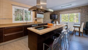 A modern kitchen with a central island, built-in appliances, and a dining area with bar stools. - Villa Bachata with private pool Bonaire (Alcúdia)