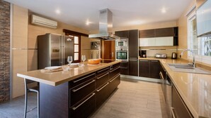 A modern kitchen with stainless steel appliances, a large island, and a built-in oven. - Villa Bachata with private pool Bonaire (Alcúdia)
