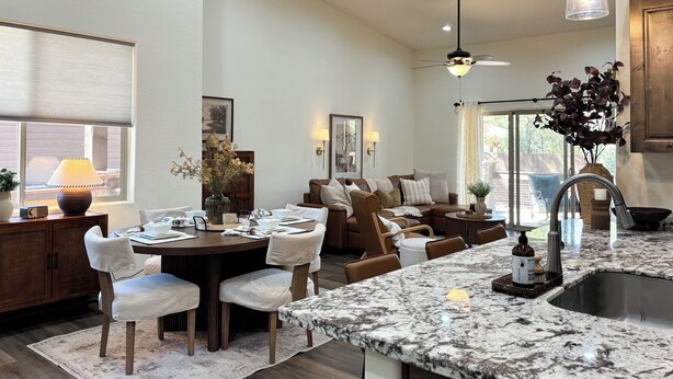 Une cuisine moderne dotée d’un plan de travail en granit, un coin repas avec une table ronde et des chaises, et un espace salon confortable avec un canapé et des fauteuils.