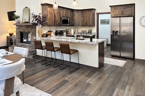 Una cocina moderna con armarios de madera oscura, un refrigerador de acero inoxidable y una isla de mármol con taburetes de bar.