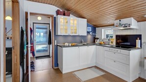 A modern kitchen with white cabinets, a black countertop, and a wooden ceiling.