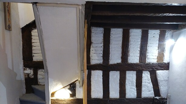 A dining area with a table and chairs, a staircase, and exposed wooden beams. - Gien bridge (Gien)