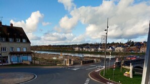 A roundabout with cars, a pedestrian crossing, and a view of a river and buildings in the background. - Gien bridge (Gien)
