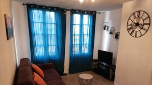A living room with a brown sofa, a round coffee table, and a TV stand. - Gien bridge (Gien)