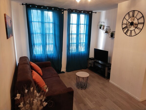 A living room with a brown sofa, a round coffee table, and a TV stand.