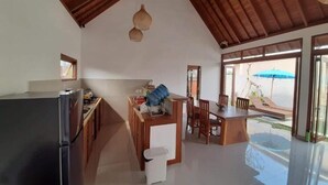 Una cocina amplia con un refrigerador moderno, armarios de madera y una zona de comedor con mesa y sillas.