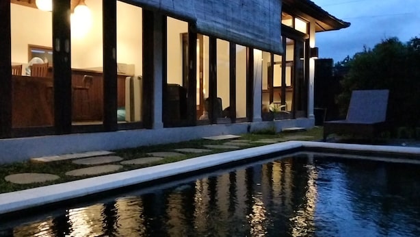 Una casa moderna con piscina, amplias ventanas y un camino de piedra que conduce a la piscina.