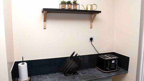 Una encimera de cocina con un tostador, un dispensador de toallas de papel y un bloque de cuchillos.