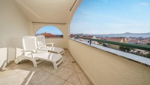 Un balcon avec des chaises blanches et une vue sur une ville côtière.