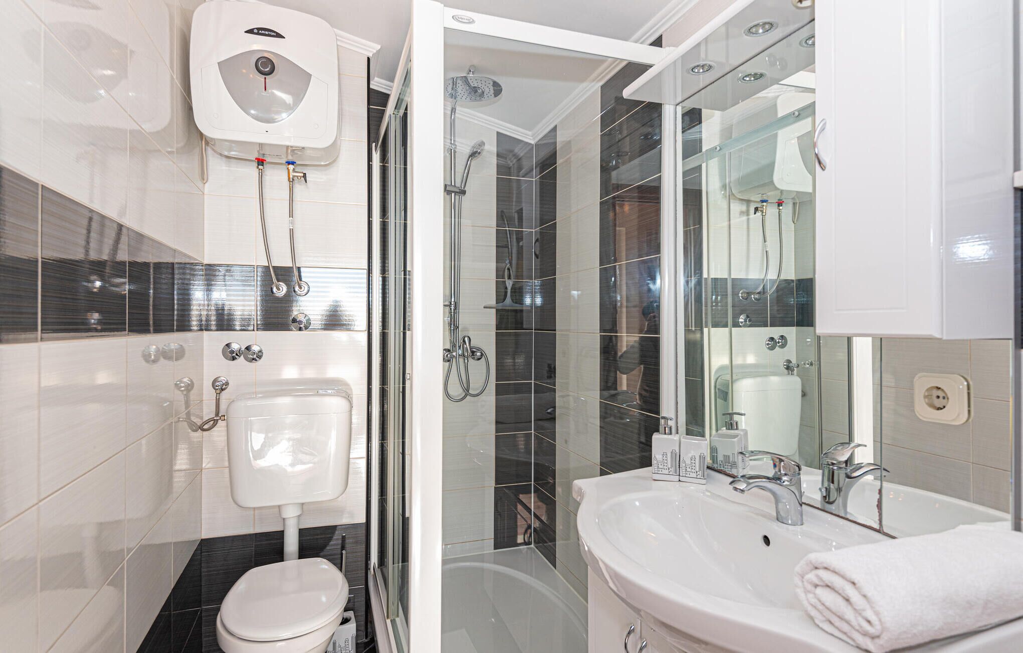 Et stilfuldt badeværelse med toilet, bidet, brusebad og vask.
