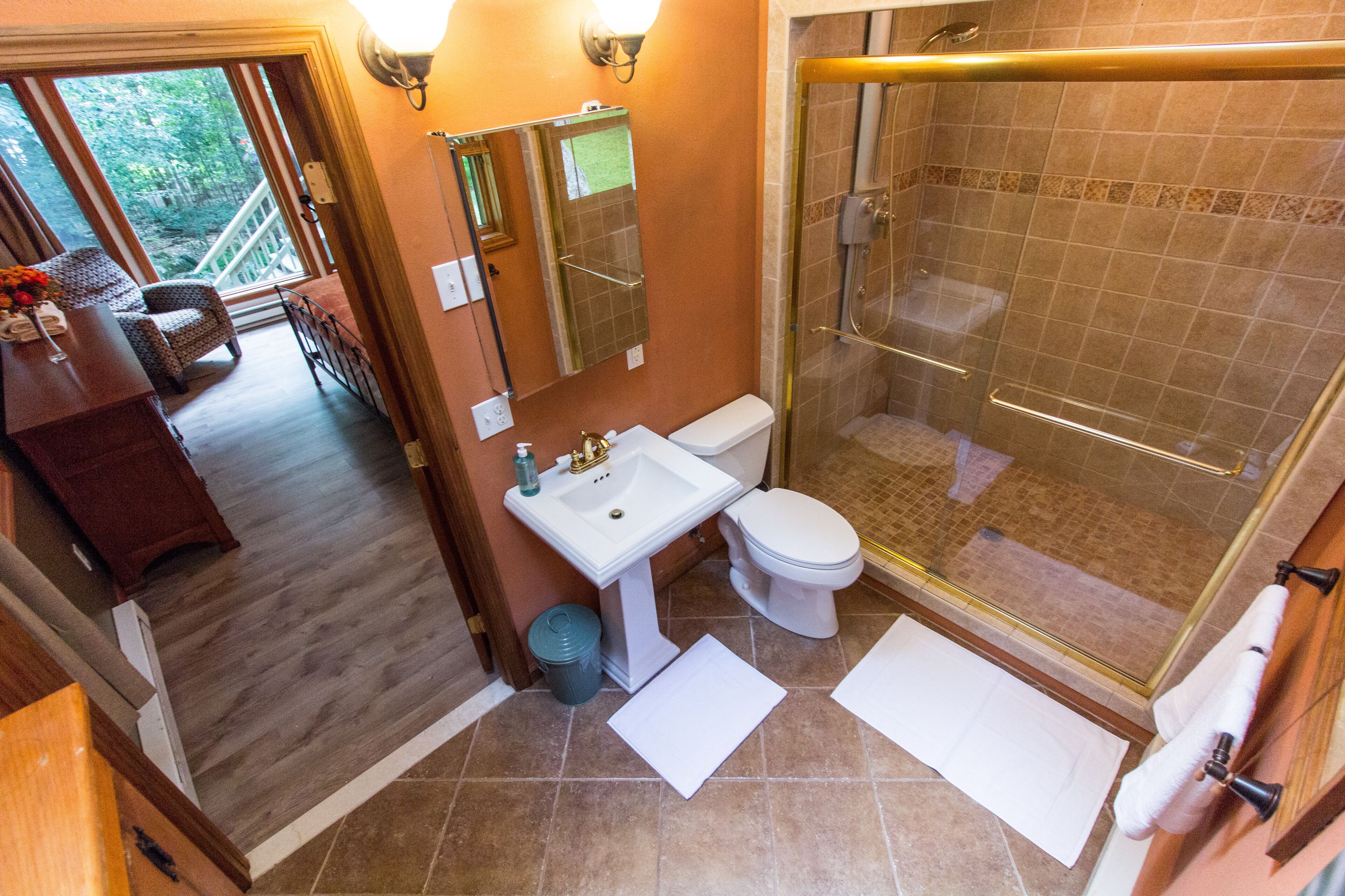 Une salle de bain avec une douche, des toilettes, un lavabo et une grande fenêtre.