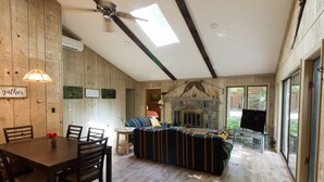 Un vaste espace de vie doté d’un plancher en bois, d’un canapé, d’une table à manger avec des chaises et d’une cheminée.